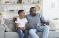 African Grandfather And Grandson Using Laptop Together, Watching Movie At Home Royalty Free Stock Photo