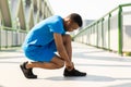 African guy in a blue sports suit tying his shoelaces on his sneakers before jogging Royalty Free Stock Photo