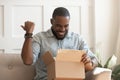 Happy african guy opening long-awaited parcel box Royalty Free Stock Photo