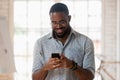 African guy holds phone using apps take break during workday Royalty Free Stock Photo