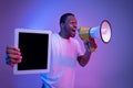 African Guy Making Announcement With Loudspeaker And Holding Digital Tablet, Neon Lighting Royalty Free Stock Photo