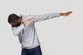 African guy performing dabbing dance isolated on grey studio background