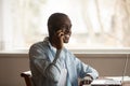 African guy sit at table near computer talk on smartphone Royalty Free Stock Photo