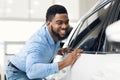 African Guy Touching His New Vehicle In Dealership Showroom Royalty Free Stock Photo