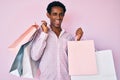 African handsome man holding shopping bags winking looking at the camera with sexy expression, cheerful and happy face Royalty Free Stock Photo