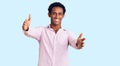 African handsome man wearing casual pink shirt looking at the camera smiling with open arms for hug Royalty Free Stock Photo