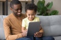 Black father teaching little son use tablet electronic device Royalty Free Stock Photo