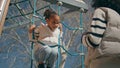 African kid climbing rope ladder sunny day. Little girl playing on playground Royalty Free Stock Photo