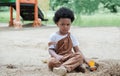 African little boy stare at the camera with an angry expression while playing sand with toys loader on playground