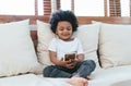 African little cute boy sitting on sofa using smartphone watching cartoons having fun enjoy on-line app for kids in living room at Royalty Free Stock Photo