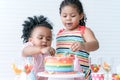 African little cute child girl enjoy eating rainbow cake, sugar candies and jelly on birthday party by hand and spoon with her