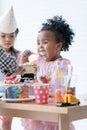 African little cute child girl use spoon enjoy eating big bite rainbow cake, sugar candies and jelly on birthday party with Royalty Free Stock Photo