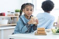 African little girl smiling, holding homemade sandwiches in hands, standing in kitchen at home with brother, prepare food for Royalty Free Stock Photo