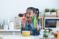 African little kid girl having fun with food and vegetables at kitchen, eating tomato and holding green vegetable. Cute child Royalty Free Stock Photo