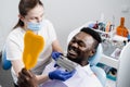 African is looking at veneers or implants teeth color matching samples in doctor hands. Dentistry. Dentist showing teeth Royalty Free Stock Photo