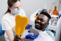 African is looking at veneers or implants teeth color matching samples in doctor hands. Dentistry. Dentist showing teeth Royalty Free Stock Photo
