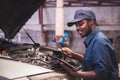 African maintenance male checking car, service via insurance system at automobile repair and check up center