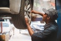 African maintenance male checking car, service via insurance system at automobile repair and check up center