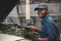 African maintenance male checking car with use wrench and tablet , service via insurance system at Auomobile repair and check up