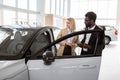 African male car dealer standing with client of dealership in showroom. Royalty Free Stock Photo