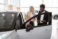 African male car dealer standing with client of dealership in showroom. Royalty Free Stock Photo