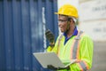 African male dock worker control loading containers cargo at warehouse container shipyard. Marine and carrier staff employee.