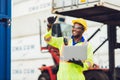 African male dock worker control loading containers cargo at warehouse container shipyard. Marine and carrier staff employee.