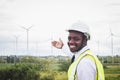 African male engineers working on site with wind turbine propeller on the background. Alternative energy, environmental friendly