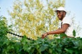 African male gardener in uniform and glasses trimming bushes Royalty Free Stock Photo