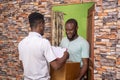 African male receiving a parcel from a delivery service worker