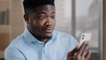 African male surprised amazed millennial 30s man worker talking remote on mobile phone handsome american adult guy make Royalty Free Stock Photo