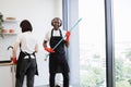 African male worker washes windows, having fun while holding mop like guitar. Royalty Free Stock Photo