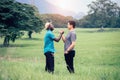 African man and asian man travelers standing and shaking hand in the green nature background.Concept of best friends