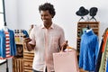 African man with curly hair holding shopping bags using smartphone smiling and laughing hard out loud because funny crazy joke Royalty Free Stock Photo
