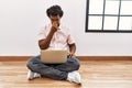 African man with curly hair using laptop sitting on the floor tired rubbing nose and eyes feeling fatigue and headache Royalty Free Stock Photo