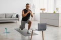 African Man Doing Forward Lunge Exercise Watching Online Workout Indoor