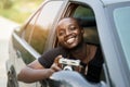 African man driver holding a film camera and smiling while sitting in a car with open front window Royalty Free Stock Photo