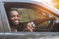 African man driver holding a film camera and smiling while sitting in a car with open front window Royalty Free Stock Photo