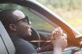 African man driver holding a film camera and smiling while sitting in a car with open front window Royalty Free Stock Photo