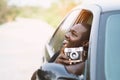 African man driver holding a film camera and smiling while sitting in a car with open front window Royalty Free Stock Photo