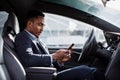 African man driving car and using modern smartphone Royalty Free Stock Photo