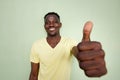 African man gesturing thumbs up sign by green wall Royalty Free Stock Photo