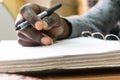 African man holding pen in hand to write on blank white paper Royalty Free Stock Photo