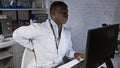 African man in lab coat expresses discomfort at workplace in laboratory Royalty Free Stock Photo