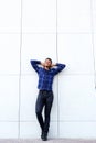 African man leaning against wall with hands behind head Royalty Free Stock Photo