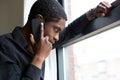 African man looking out window and talking on cellphone Royalty Free Stock Photo