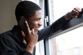 African man looking out window and talking on mobile phone Royalty Free Stock Photo
