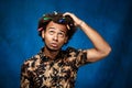 African man with markers in hair thinking over blue background.