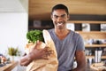 African man, paper bag and groceries in home kitchen with smile for discount, deal and nutrition choice. Person Royalty Free Stock Photo