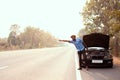 African man raising hands for help because his car is broken side the highway